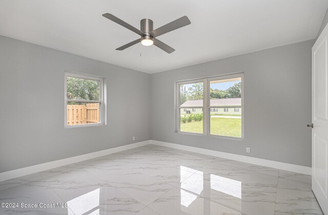 empty room featuring ceiling fan and plenty of natural light