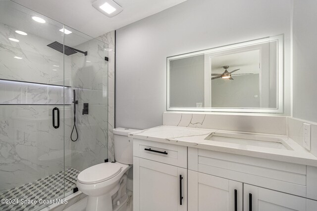 bathroom with ceiling fan, a shower with shower door, vanity, and toilet