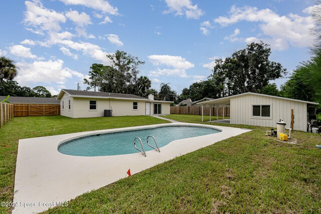 view of swimming pool featuring central AC unit, a patio area, and a yard