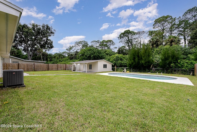 view of yard with central air condition unit, an outdoor structure, and a fenced in pool