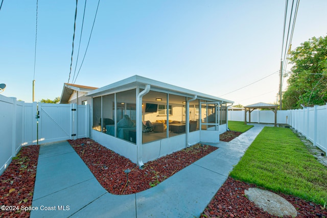 back of house with a lawn and a sunroom