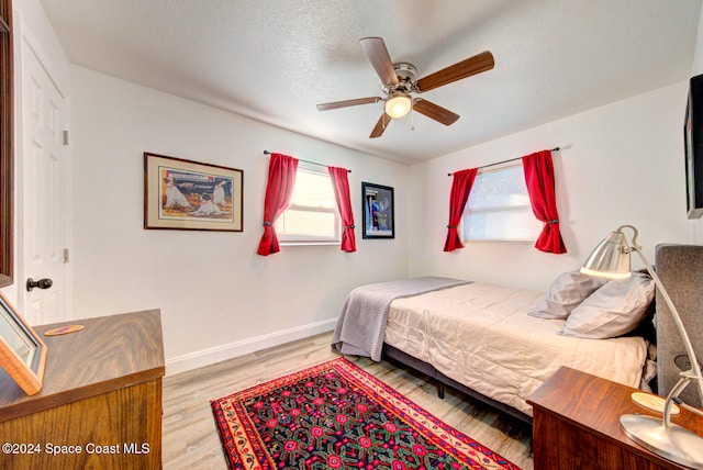 bedroom with light wood-type flooring, a textured ceiling, and ceiling fan