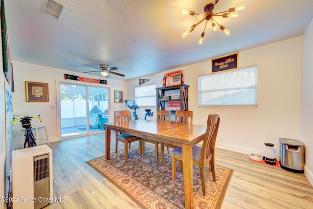 dining space featuring ceiling fan with notable chandelier, a textured ceiling, and light hardwood / wood-style flooring