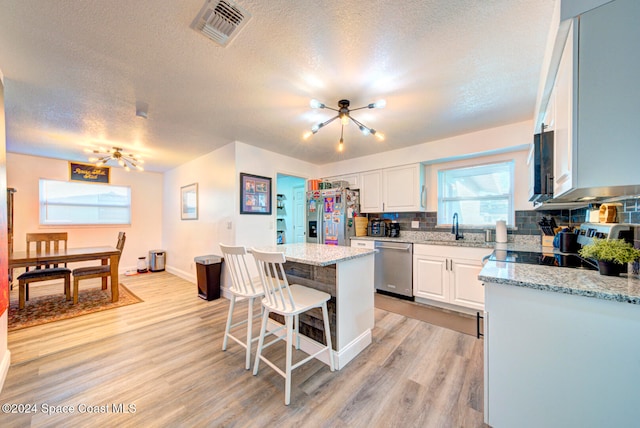 kitchen with white cabinetry, appliances with stainless steel finishes, a textured ceiling, and a center island