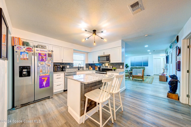 kitchen with white cabinetry, appliances with stainless steel finishes, decorative backsplash, and light hardwood / wood-style floors