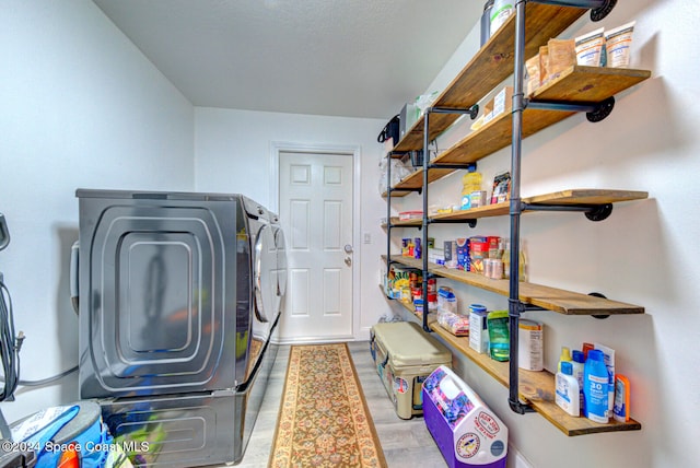 laundry room with washing machine and clothes dryer and light hardwood / wood-style floors