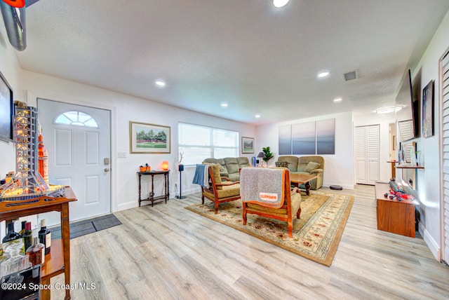 living room featuring light wood-type flooring and a textured ceiling