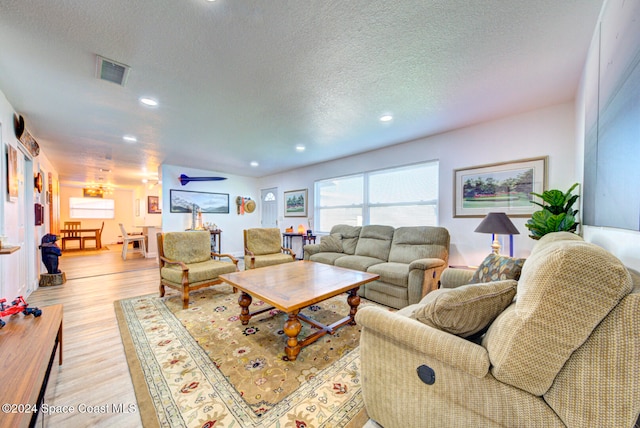 living room featuring light wood-type flooring and a textured ceiling