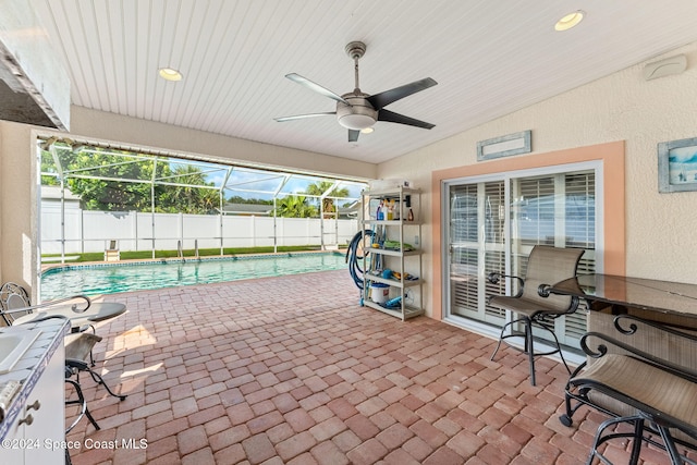 view of patio / terrace featuring ceiling fan, a fenced in pool, and glass enclosure