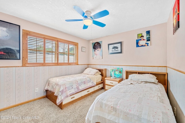 carpeted bedroom with ceiling fan and a textured ceiling