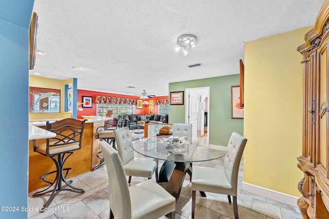 dining space featuring ceiling fan and a textured ceiling