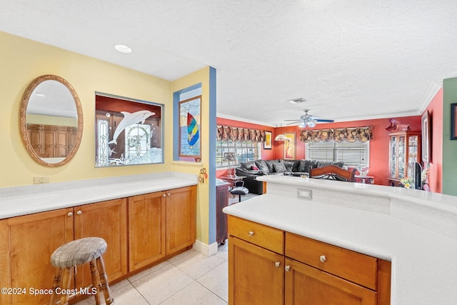 kitchen with light tile patterned floors, crown molding, a textured ceiling, and ceiling fan