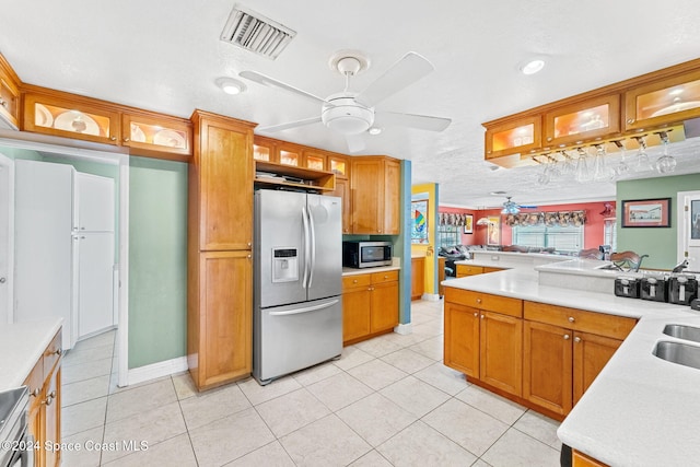 kitchen with a textured ceiling, kitchen peninsula, appliances with stainless steel finishes, and light tile patterned floors