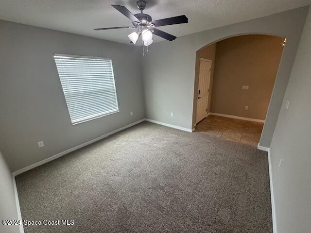 carpeted spare room with ceiling fan