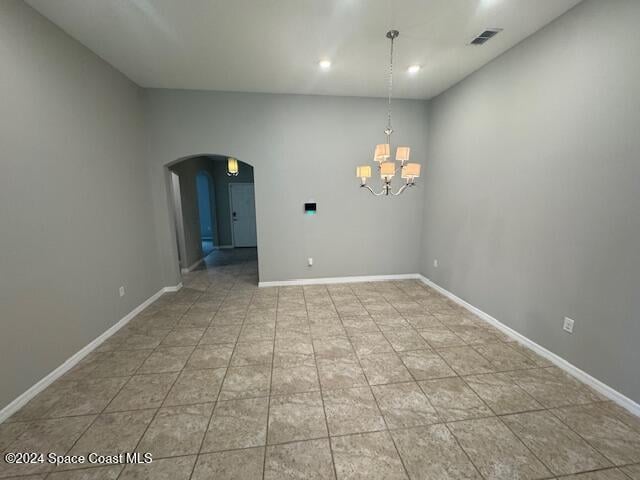 tiled spare room with a notable chandelier