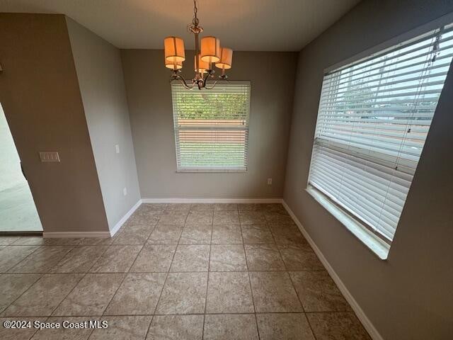 unfurnished dining area with a notable chandelier and light tile patterned floors