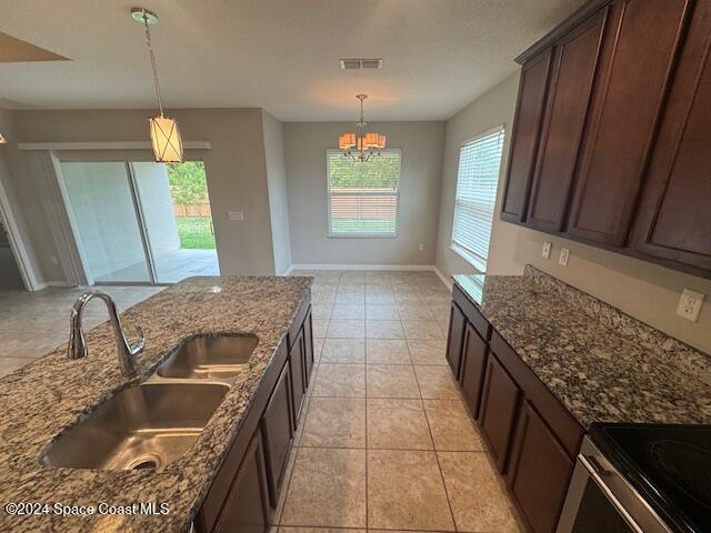 kitchen featuring hanging light fixtures, dark stone counters, and sink