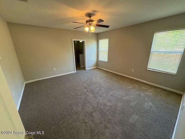 carpeted spare room featuring ceiling fan and plenty of natural light