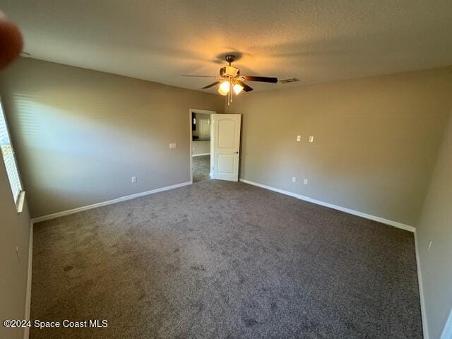 spare room with dark colored carpet and ceiling fan