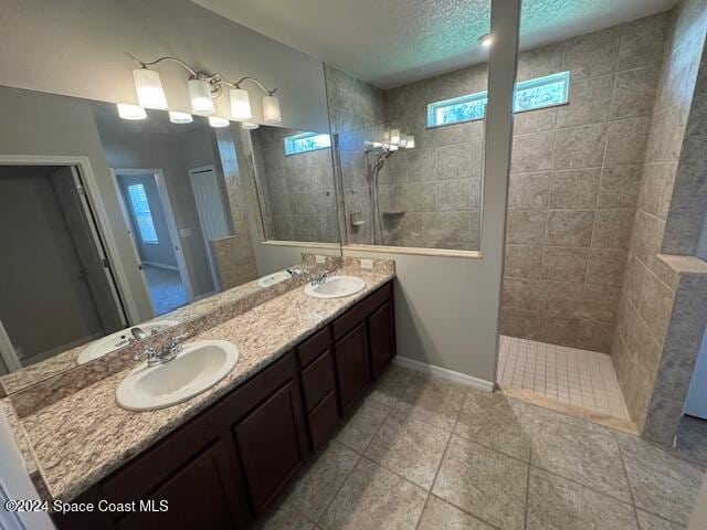 bathroom featuring vanity, tile patterned floors, a textured ceiling, and tiled shower