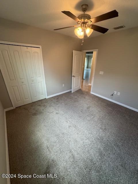 unfurnished bedroom featuring a closet, ceiling fan, and carpet floors