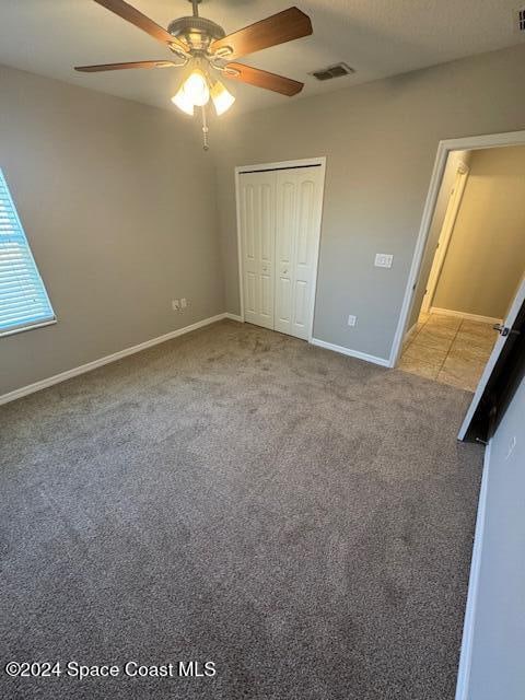 unfurnished bedroom with carpet flooring, ceiling fan, and a closet