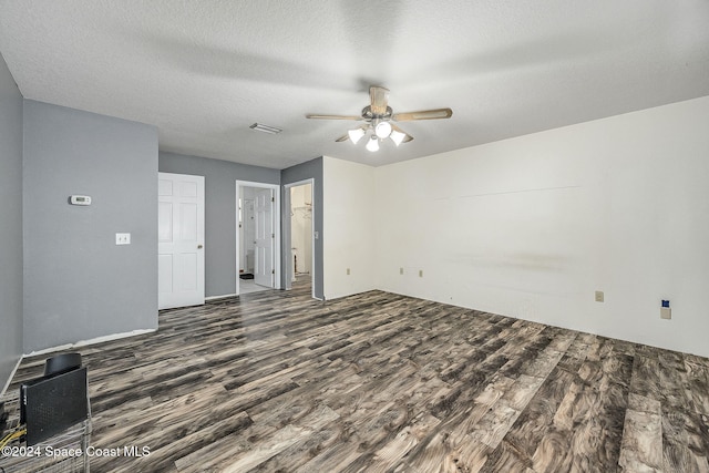 empty room with ceiling fan, dark hardwood / wood-style flooring, and a textured ceiling