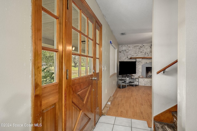 doorway to outside featuring light tile patterned flooring and a stone fireplace
