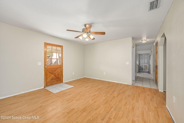 spare room featuring a textured ceiling, light hardwood / wood-style floors, and ceiling fan