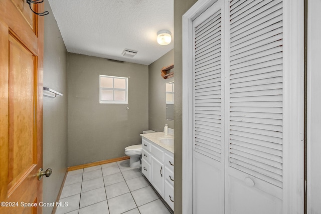 bathroom featuring tile patterned flooring, a textured ceiling, vanity, and toilet
