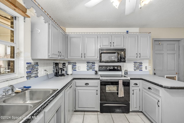 kitchen featuring decorative backsplash, light tile patterned floors, sink, and black appliances