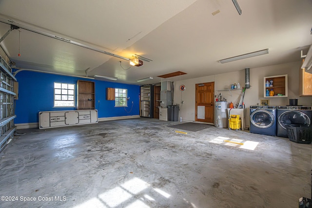 garage with washing machine and dryer, electric water heater, and a garage door opener