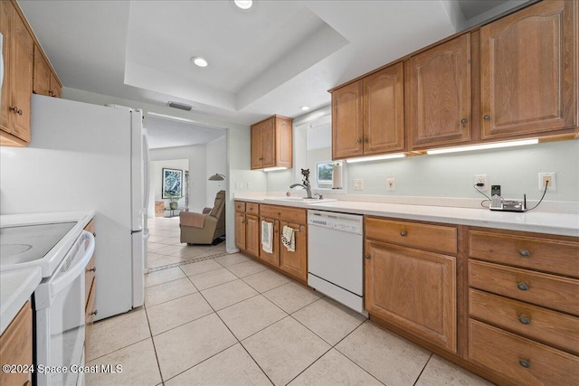 kitchen featuring a raised ceiling, sink, light tile patterned flooring, and white appliances