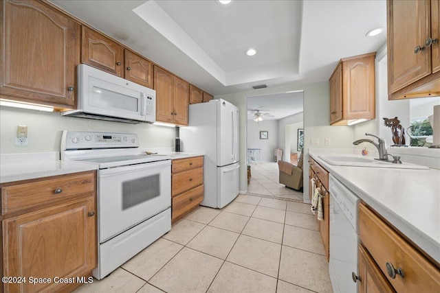 kitchen featuring white appliances, a raised ceiling, sink, ceiling fan, and light tile patterned floors