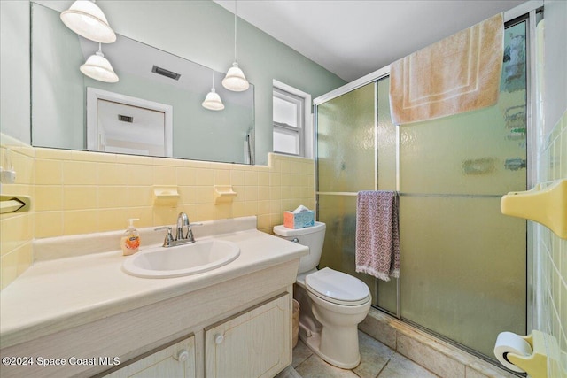 bathroom featuring vanity, tile patterned flooring, toilet, tile walls, and a shower with shower door