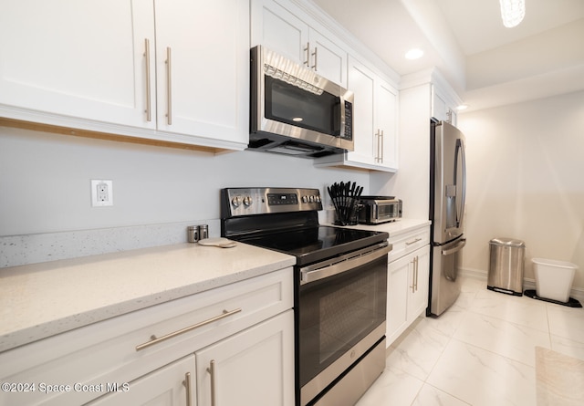 kitchen featuring white cabinetry, stainless steel appliances, and light stone counters