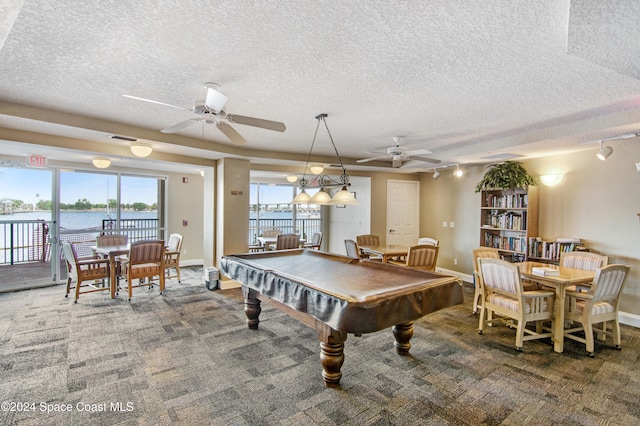 rec room featuring a water view, a textured ceiling, and dark colored carpet