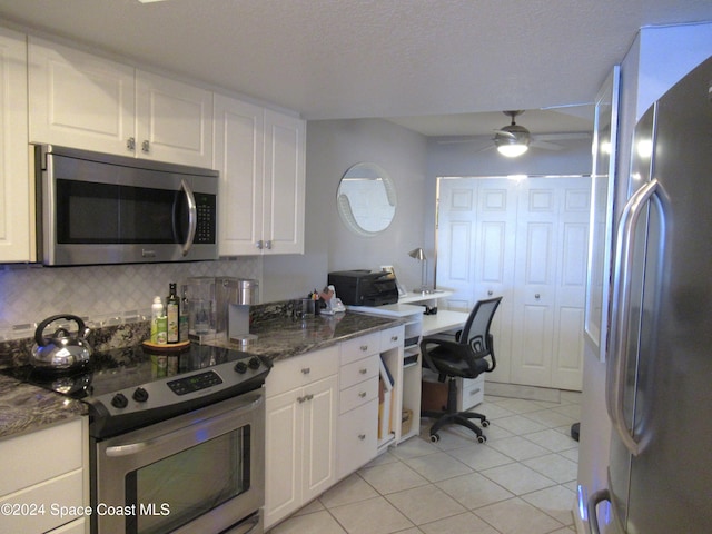 kitchen with light tile patterned flooring, appliances with stainless steel finishes, white cabinets, dark stone counters, and backsplash