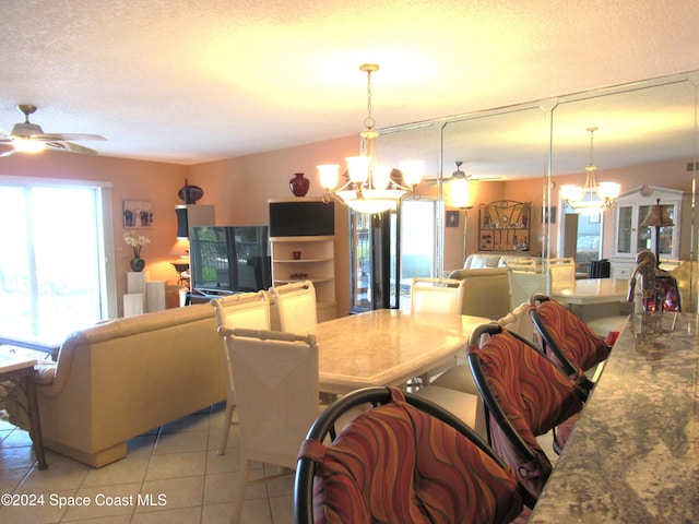 tiled dining room with ceiling fan with notable chandelier and a textured ceiling