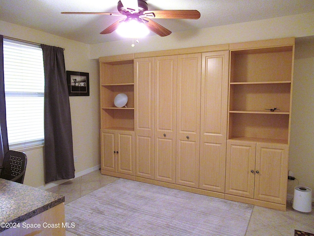 unfurnished bedroom with ceiling fan, multiple windows, and light tile patterned floors