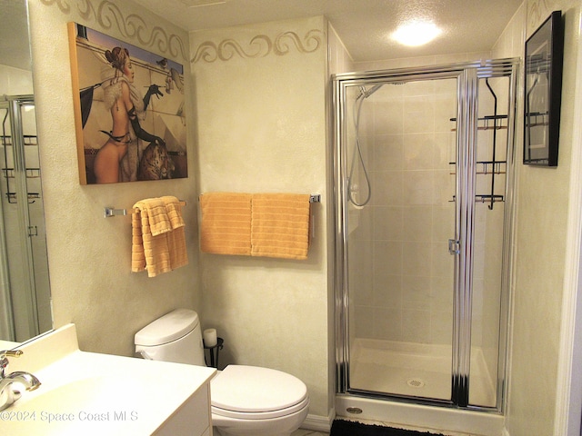 bathroom featuring vanity, a shower with shower door, a textured ceiling, and toilet