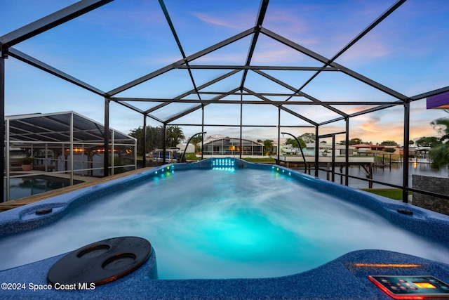 pool at dusk featuring a water view and a lanai