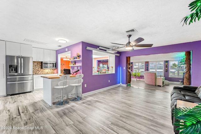 kitchen with white cabinets, appliances with stainless steel finishes, backsplash, and a kitchen breakfast bar