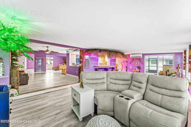 living room featuring an AC wall unit, ceiling fan, a healthy amount of sunlight, and light wood-type flooring