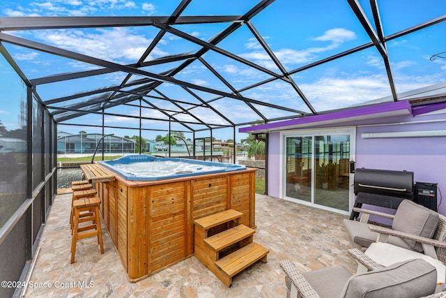 view of patio featuring glass enclosure, an outdoor bar, and a hot tub