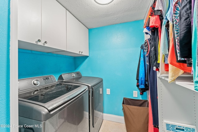 laundry room with cabinets, a textured ceiling, and washing machine and clothes dryer