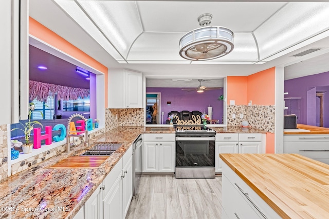 kitchen with wood counters, light hardwood / wood-style flooring, tasteful backsplash, white cabinetry, and stainless steel appliances