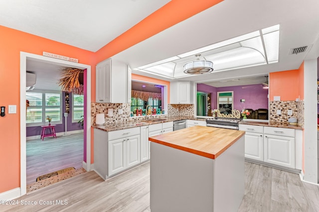 kitchen with backsplash, white cabinetry, kitchen peninsula, and light hardwood / wood-style flooring