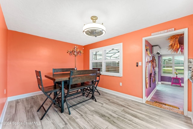 dining area with a wall mounted AC and light wood-type flooring