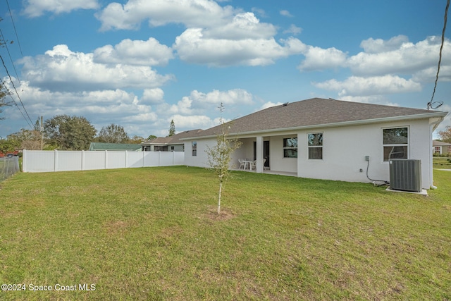 rear view of house with cooling unit and a lawn